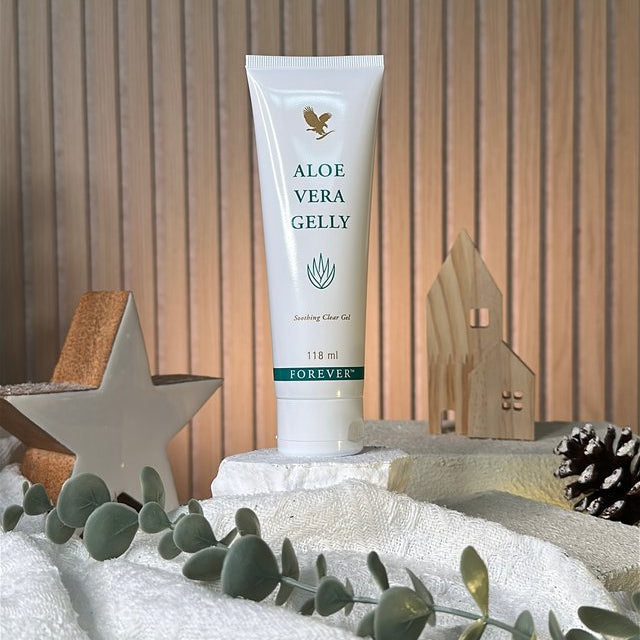 Tube of aloe vera gel on a decorative surface with greenery and wooden background